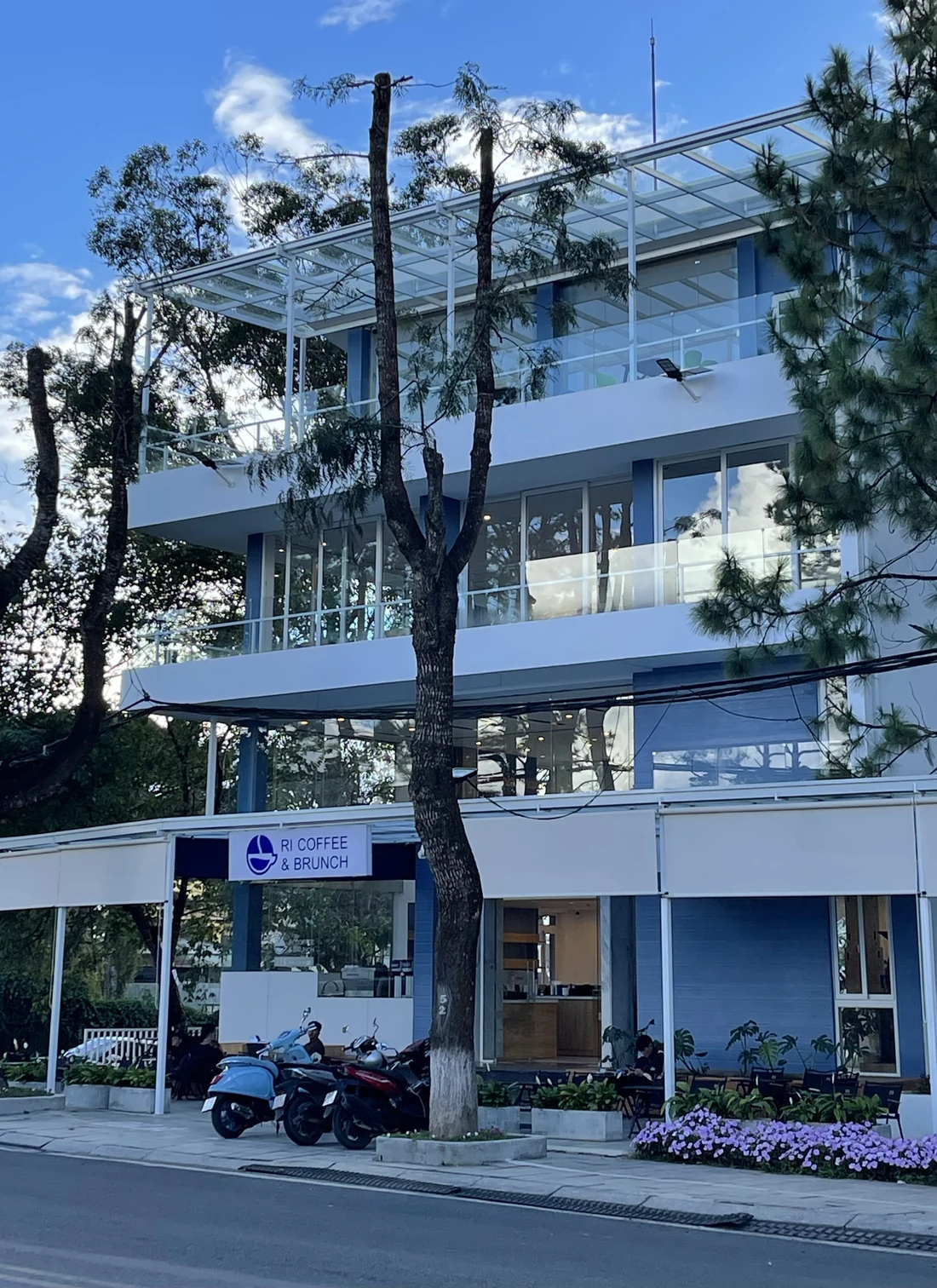 Biển hiệu ORI Coffee & Brunch trên mặt tiền xanh và trắng, dưới những tán thông Đà Lạt.